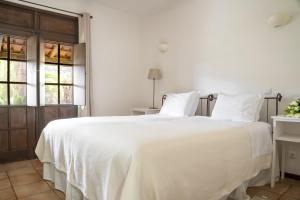 - une chambre avec un grand lit blanc et des draps blancs dans l'établissement Casas de Campo do Pomar B&B - Self Check-in, à Santana
