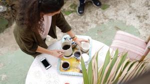 een vrouw met een dienblad koffiekopjes op een tafel bij Camino Art House in Vega de San Mateo