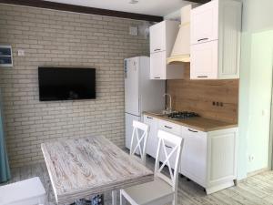 a kitchen with white cabinets and a table with chairs at Шале Леона in Arkhyz