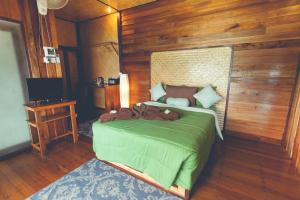 ein Schlafzimmer mit einem grünen Bett und einer Holzwand in der Unterkunft Bayview Hill Resort in Ko Lipe