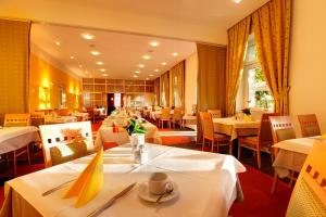 un comedor con mesas y sillas blancas y registradora en Strandhotel Alte Donau, en Viena