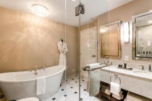 a bathroom with a tub, sink, mirror and bathtub at Hôtel Birks Montréal in Montreal