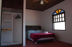 1 dormitorio con 1 cama con manta roja y ventana en pousada bella canas, en Florianópolis