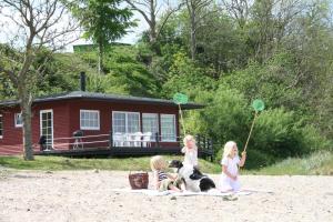 3 filles et un chien assis sur une couverture sur la plage dans l'établissement Loff Holiday Houses, à Åbenrå