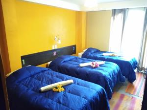 a room with three blue beds with toys on them at Hostal Lucky Puno in Puno