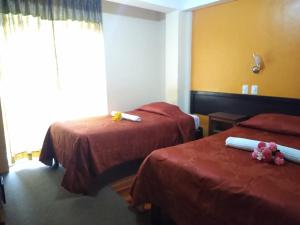 a hotel room with two beds and a window at Hostal Lucky Puno in Puno