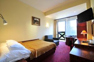 a hotel room with a bed and a desk and a television at Hotel Continental in Krynica Morska