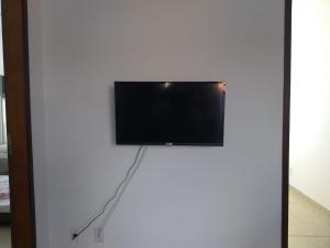 Elle comprend une télévision à écran plat sur un mur blanc. dans l'établissement Stay in Itatiaia, à Itatiaia
