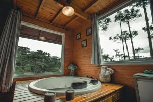 a bath tub in a room with two large windows at Eco Pousada Invernador in Urubici