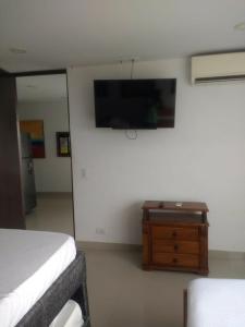 ein Schlafzimmer mit einem Bett und einem Fernseher an der Wand in der Unterkunft 1C5 APARTAMENTO EN CARTAGENA CON BALCON Y VISTA AL MAR, AIRE ACONDICIONADO Y WIFi in Cartagena de Indias