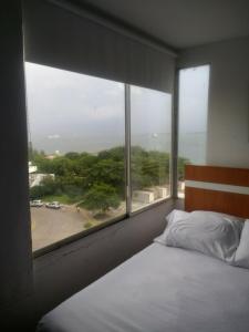 ein Schlafzimmer mit einem Bett und einem großen Fenster in der Unterkunft 1C5 APARTAMENTO EN CARTAGENA CON BALCON Y VISTA AL MAR, AIRE ACONDICIONADO Y WIFi in Cartagena de Indias