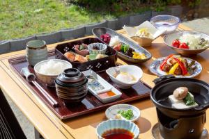 een tafel met een dienblad met eten en kommen met eten bij Ranzan in Kyoto