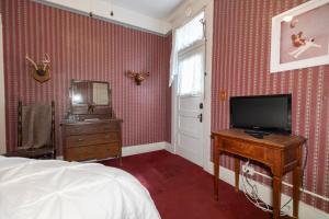 a bedroom with a bed and a television and a dresser at Bisbee Grand Hotel in Bisbee