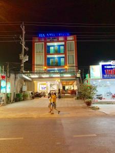 twee mensen die 's nachts voor een gebouw lopen bij Ha Anh Hotel - Mui Ne in Mũi Né