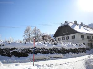 een huis bedekt met sneeuw met een vlag ervoor bij Schullerhof in Hermagor