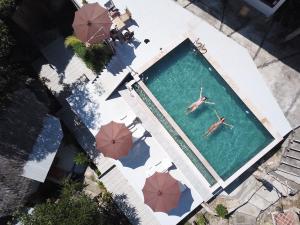 an overhead view of two people swimming in a pool with umbrellas at Chunut House Resort in Phi Phi Don
