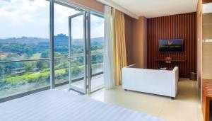 a bedroom with a white bed and a large window at Clove Hotel Bandung in Bandung