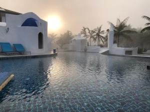 a resort swimming pool with the sun setting in the background at The Oia Pai Resort in Pai