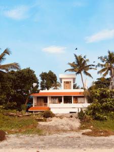 a white house on the beach with palm trees at Lemon Dew Beach House, Alleppey Beach in Alleppey