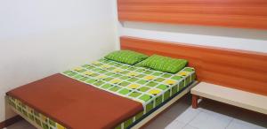a small bed with green pillows in a room at Intech Hostel in Bandung