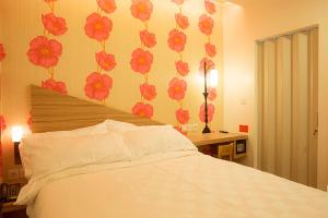 a bedroom with a bed and a wall with flowers at DeMira Hotel in Surabaya