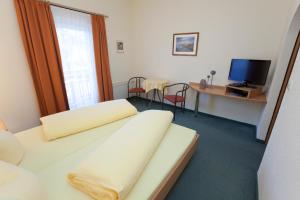 a room with a bed and a desk with a television at Hotel Garni Gletschertor in Ötztal-Bahnhof