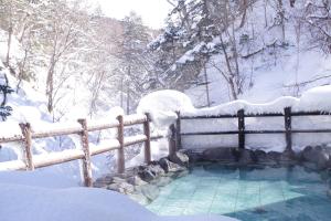 a swimming pool covered in snow next to a fence at Tomuraushionsen Higashi Taisetsuso in Shintoku