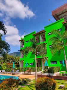 a green building with palm trees and a pool at Morakot Lanta Resort in Ko Lanta