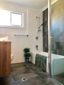 a bathroom with a tub and a toilet and a shower at Renovated Little Cottage Aberdare Hunter Valley in Aberdare