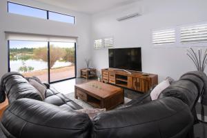 a living room with a leather couch and a flat screen tv at Wharfedale in Wilyabrup