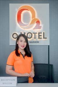 una mujer está parada frente a un cartel en O2 Hotel สกลนคร (โรงแรม โอทู สกลนคร) en Sakon Nakhon