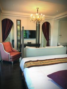 a bedroom with two beds and a chandelier and a chair at Nanta Glam CM Hotel & Residences in Chiang Mai