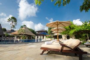 a patio with chairs and umbrellas next to a pool at Rama Beach Resort and Villas in Kuta