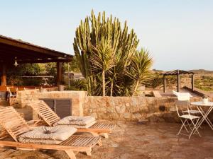 eine Terrasse mit Stühlen, einem Tisch und Stühlen in der Unterkunft TGI Dammusi Preziosi in Pantelleria