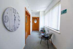 un couloir de bureau avec une horloge sur le mur et une chaise dans l'établissement Apartments Midnight City, à Dubrovnik
