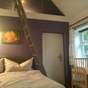 ein Schlafzimmer mit einem Etagenbett mit einer Leiter an der Wand in der Unterkunft Kleines Haus am Hafen - ruhig und grün am Ortsrand in Prerow