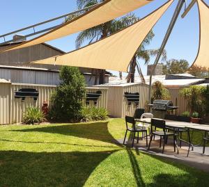 um pátio com uma mesa e cadeiras num quintal em Warrego Motel em Charleville