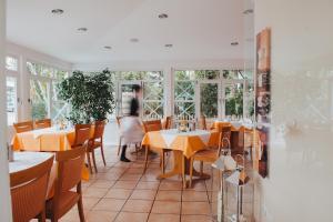 a dining room with tables and chairs and windows at Hotel Angermeier GARNI in Eching
