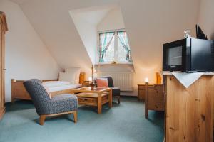 a room with a bed and a tv and chairs at Hotel Angermeier GARNI in Eching