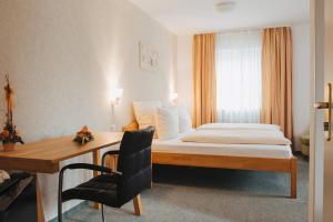 Habitación de hotel con cama, escritorio, cama y ventana en Hotel Angermeier GARNI, en Eching