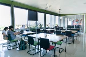 two people sitting at tables in a cafeteria with windows at Matra Co Working & Co Living in Canggu