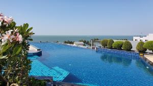 邦賢的住宿－The Patio Bangsaen，一个大型的游泳池,背景是大海