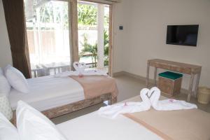 a room with two beds with towels and a television at Matra Co Working & Co Living in Canggu