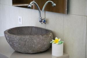a stone sink in a bathroom with a flower on a counter at Matra Co Working & Co Living in Canggu +15 photos