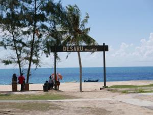 a street sign on a beach with a palm tree at Casuarina Sea Breeze Desaru in Desaru