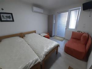 a bedroom with a bed and a chair and a window at NULI apartments in Kru&scaron;evo