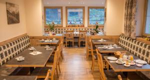 a restaurant with wooden tables and chairs and windows at Landhaus Tipotsch in Schwendau