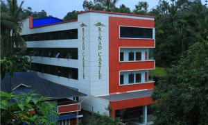 a red and white building with trees in the background at Rinad Castle Vythiri By Hamra Retreat in Vythiri