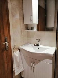 ein Badezimmer mit einem weißen Waschbecken und einem Spiegel in der Unterkunft Апартамент Легал in Tschepelare