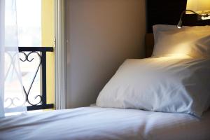 a bed with a white pillow next to a window at Hôtel Annexe in Nice